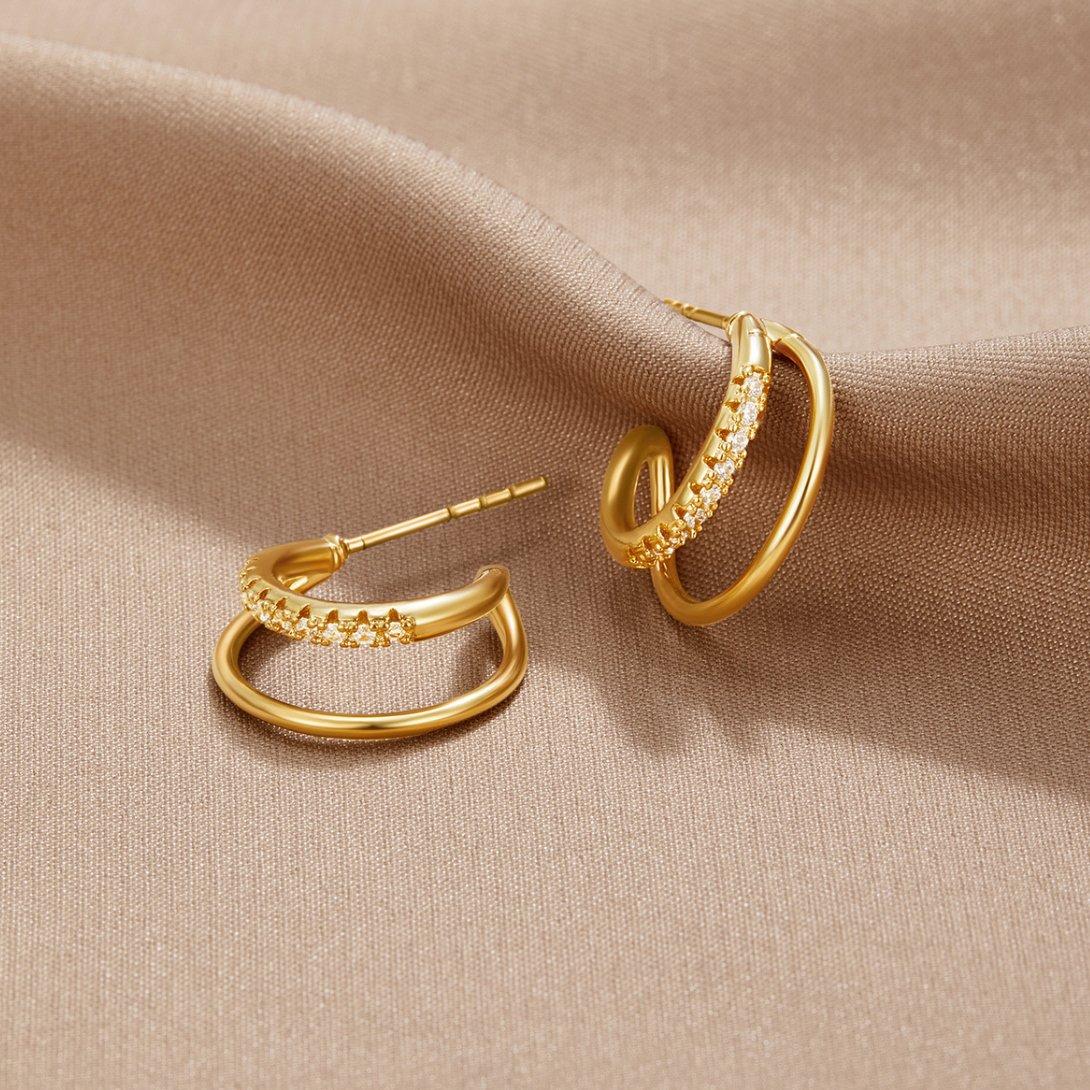 Leyla Crystal Double Hoop Earrings, pair of gold double hoop earrings on beige fabric, one
