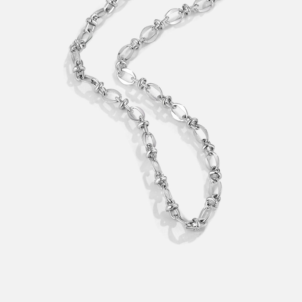 Link Chain Silver Necklace, laid out in a loose curve on a light grey surface