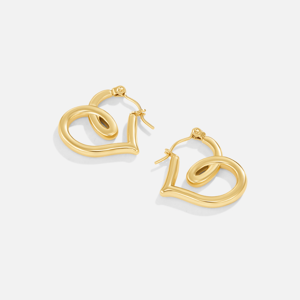 Lira Twisted Heart Hoop Earrings, pair of gold heart-shaped hoop earrings on a plain white