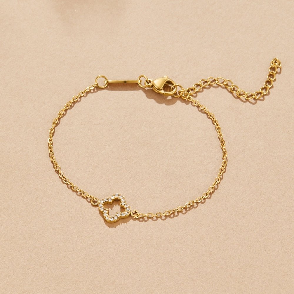 Luxe Crystal Clover Bracelet, laid flat on a beige surface, clasp and extender chain visible