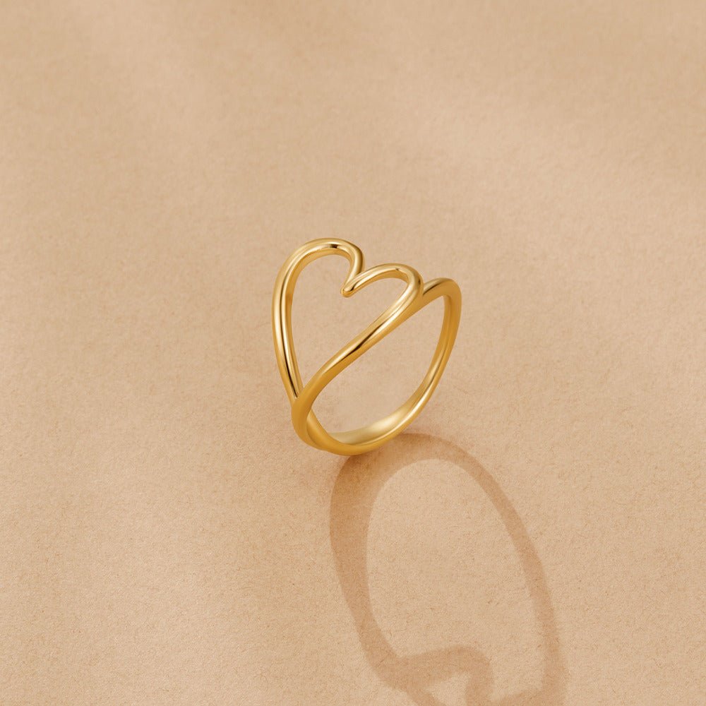 Melted Gold Heart Ring, standing upright on sand-coloured fabric, polished gold open heart band