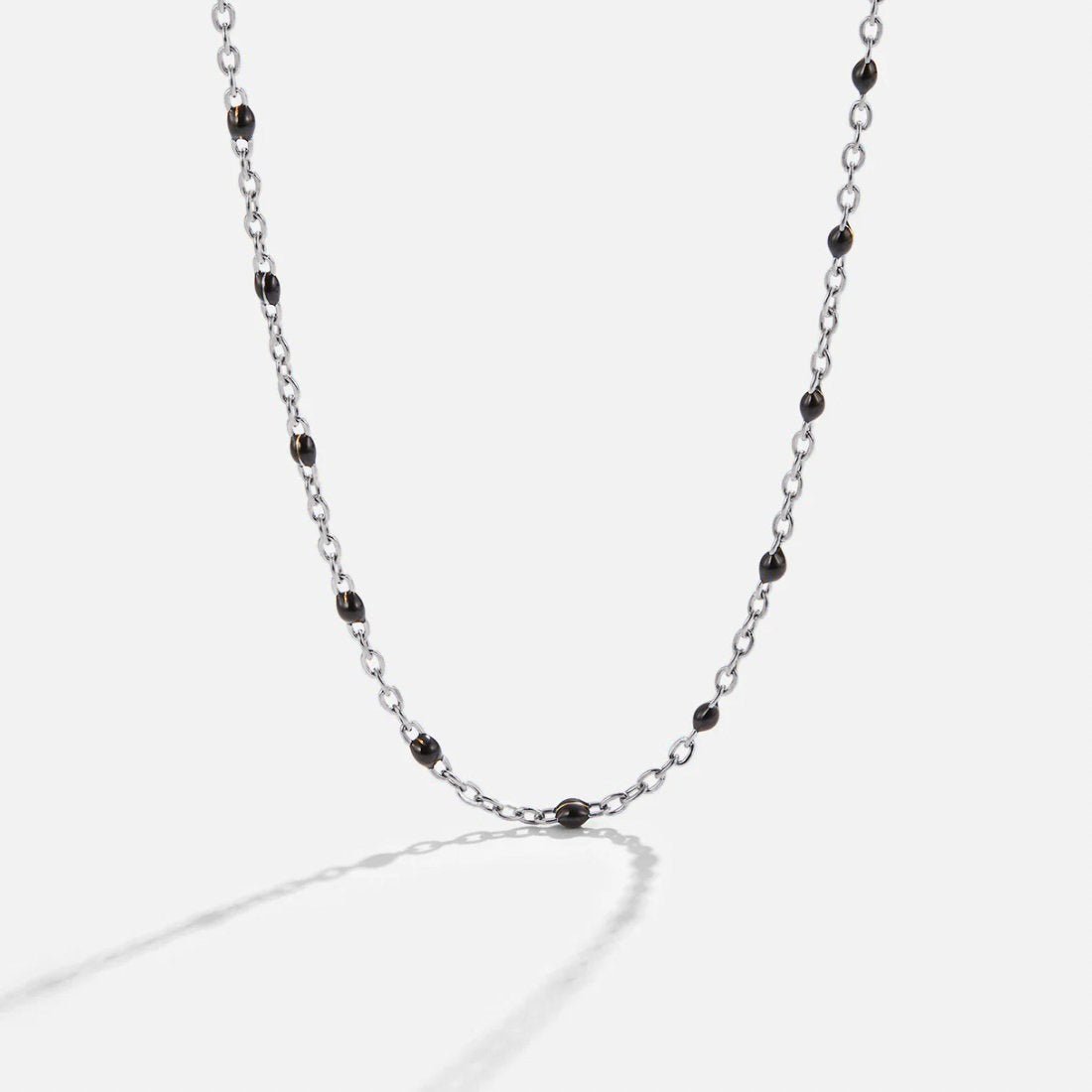 Mila Black Bead Silver Necklace, silver chain necklace laid flat on white with black enamel beads