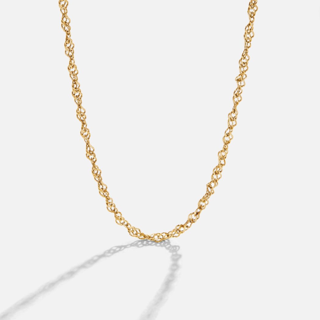 Mila Twist Gold Chain Necklace, gold twisted chain lying in a curve on a pale background