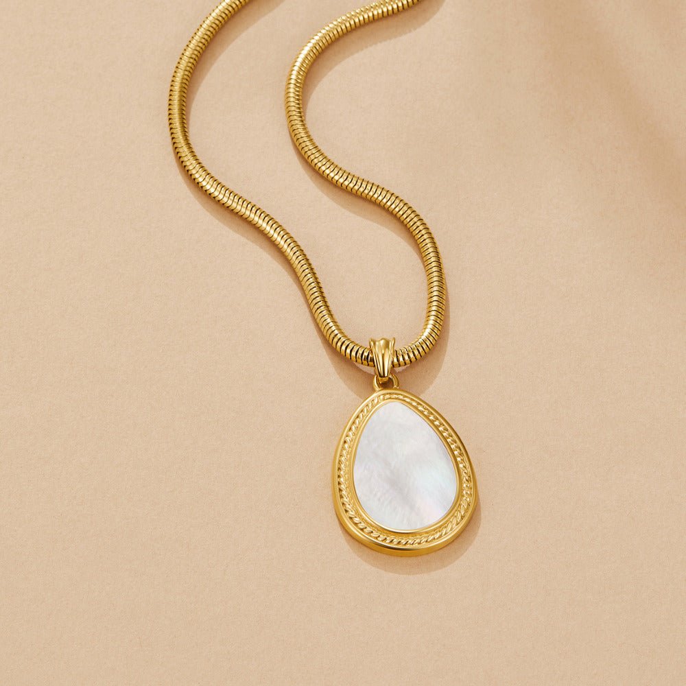 Mother of Pearl Teardrop Necklace, flat lay on beige, gold snake chain with pearly teardrop
