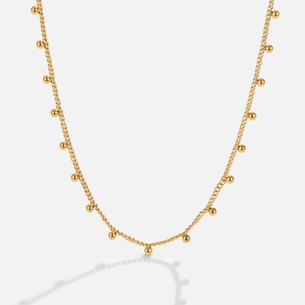 Nylah Bead Necklace, gold chain necklace laid flat on white, with small round beads hanging along it