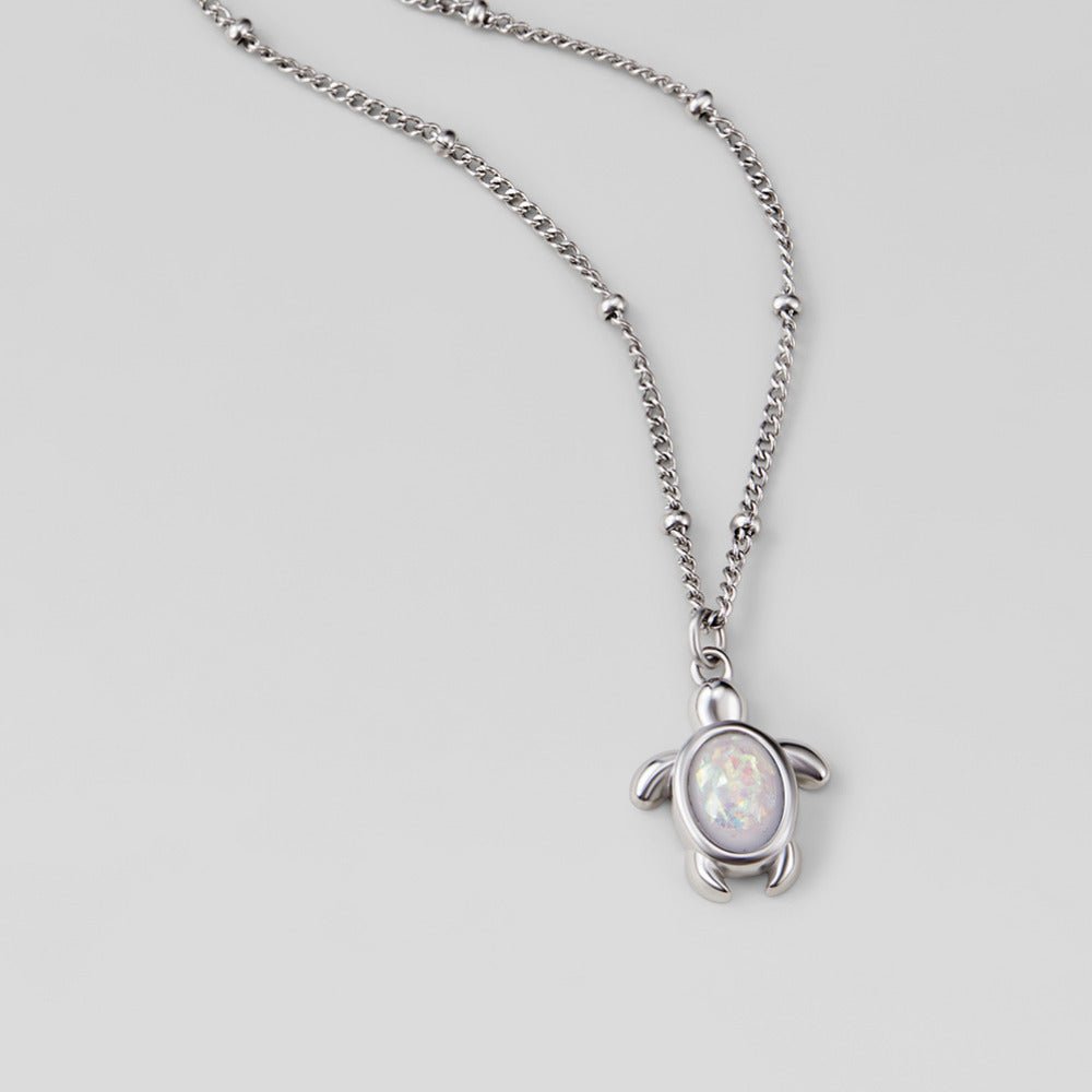 Opal Silver Turtle Pendant Necklace, flat on a grey surface, turtle pendant with opal centre