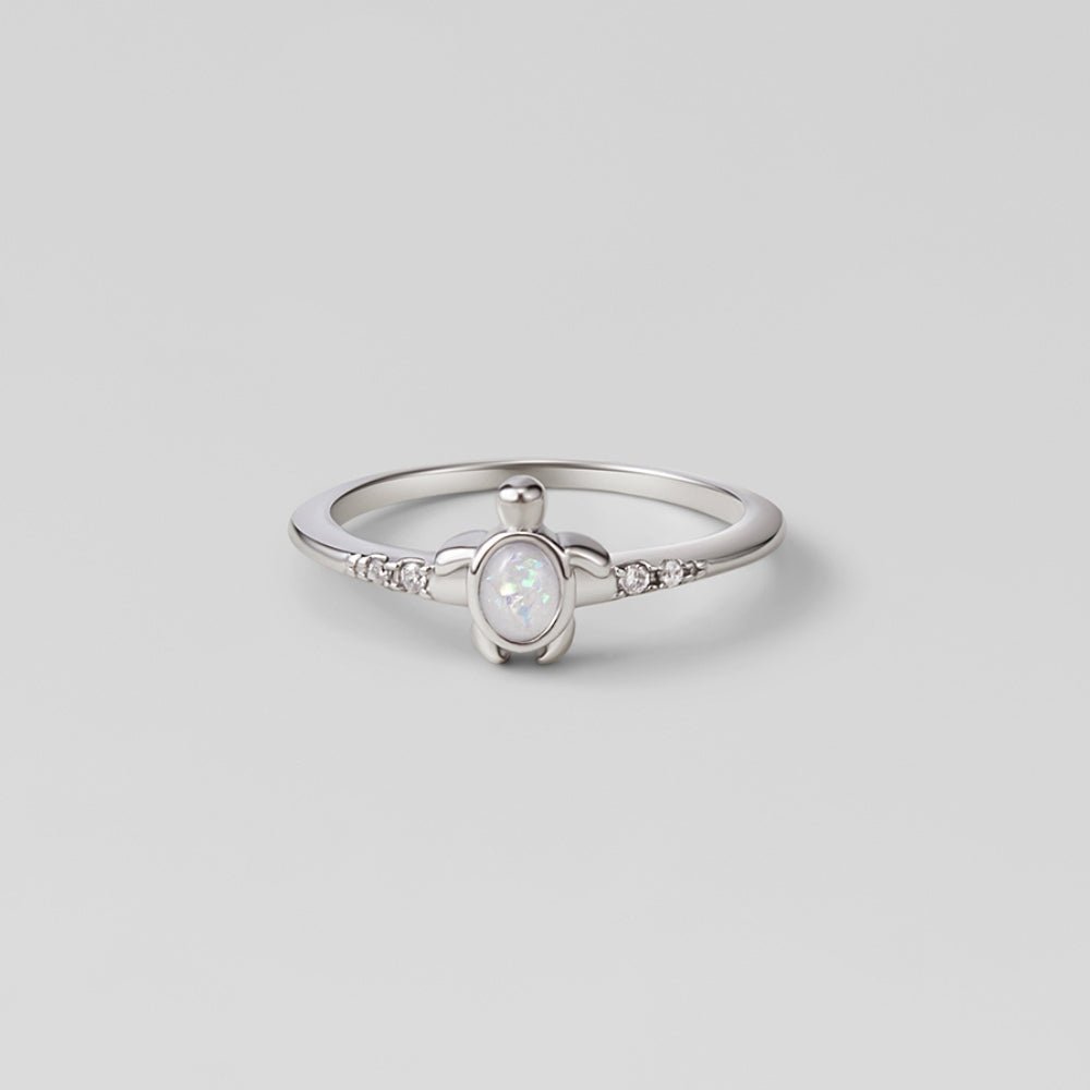 Opal Silver Turtle Ring, silver band with a turtle-shaped opal centre and small side stones, on grey