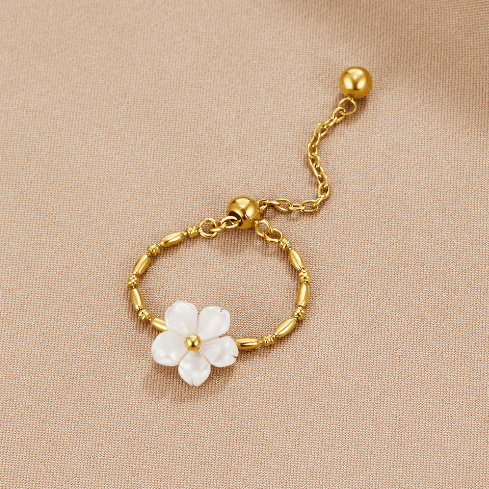 Pearl White Blossom Flower Ring, lying flat on beige fabric, gold bead band with white flower