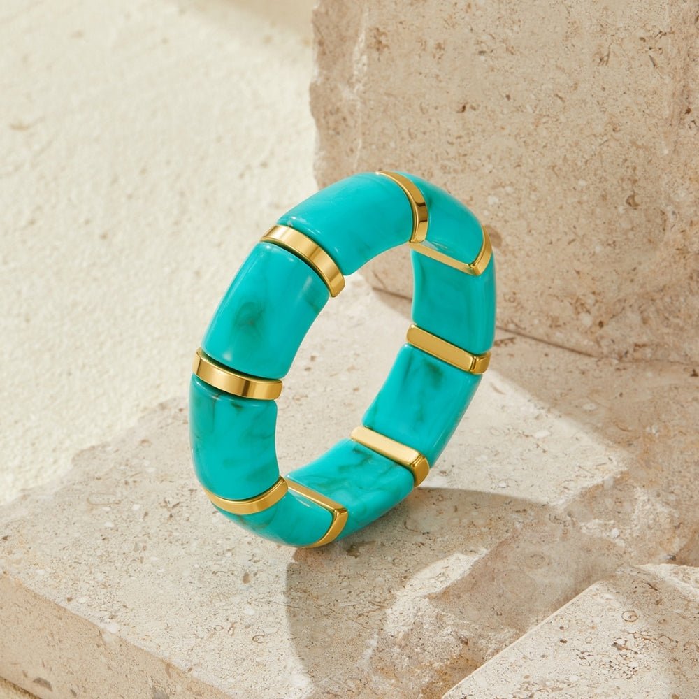 Priya Elastic Gold & Teal Bracelet, standing upright on weathered stone, turquoise segments