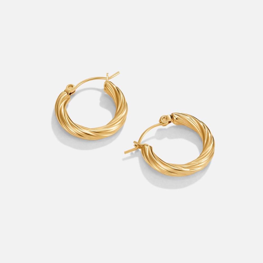 Raya Twisted Hoop Earrings, pair of gold twisted hoop earrings lying flat on white background