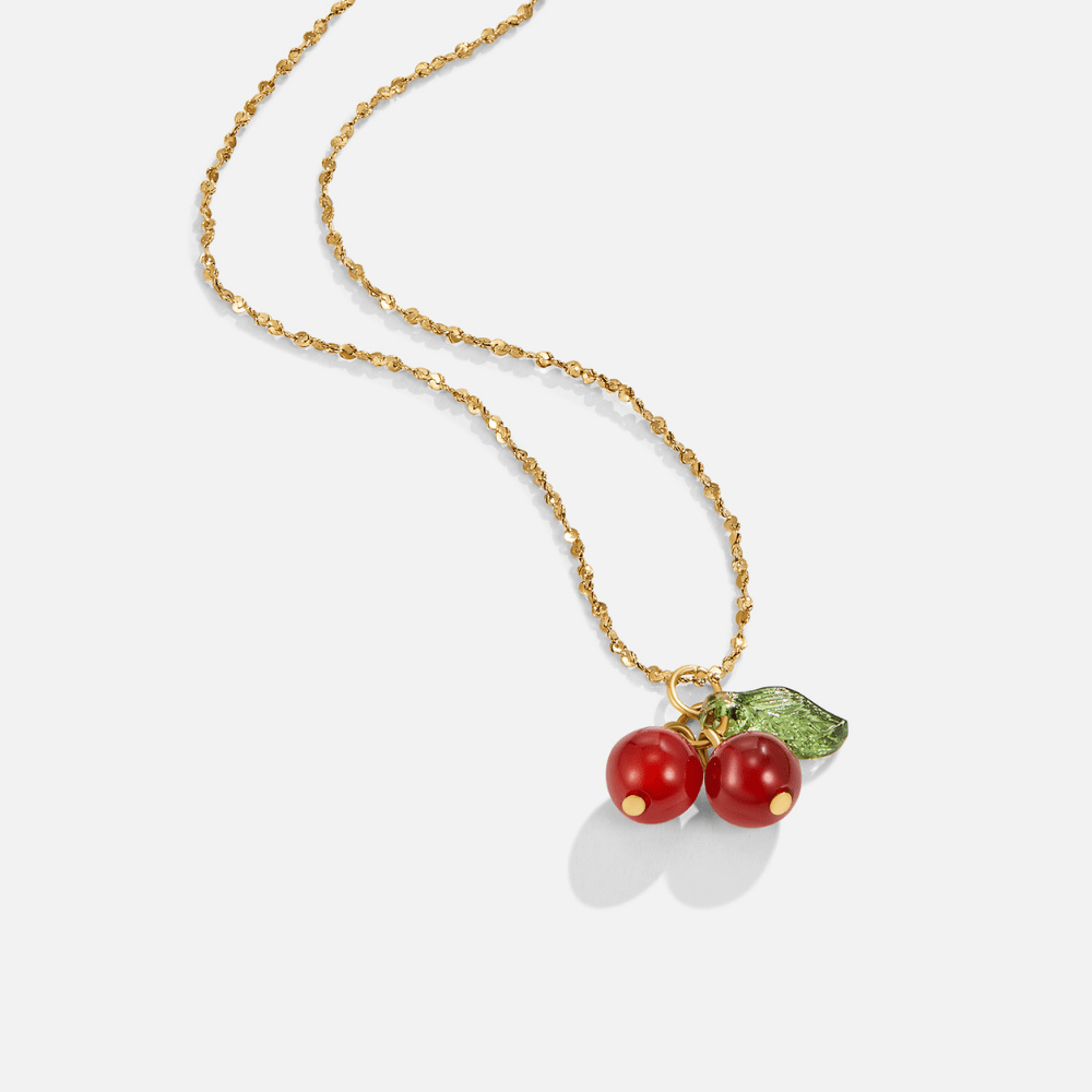 Red Cherry Pendant Necklace, laid flat on white, gold chain with red cherry charm and green
