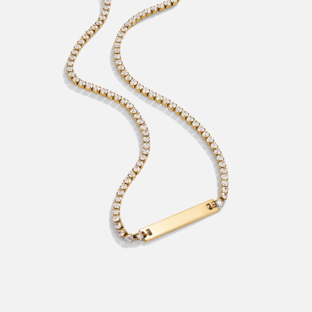 Rina Crystal Necklace, laid out on white, gold bar pendant on a crystal chain