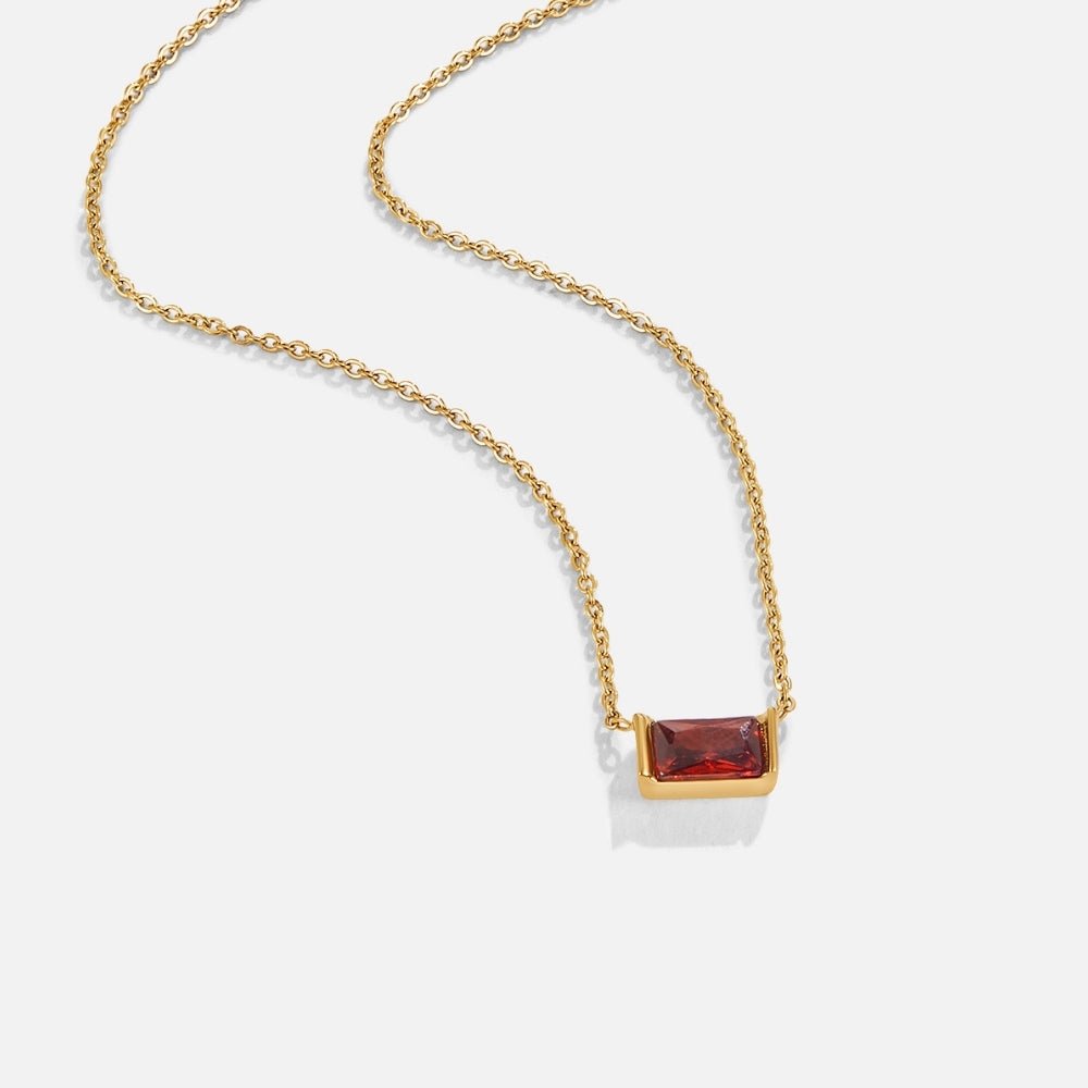 Ruby Baguette Necklace, gold chain necklace laid on white, with a red baguette-cut stone pendant