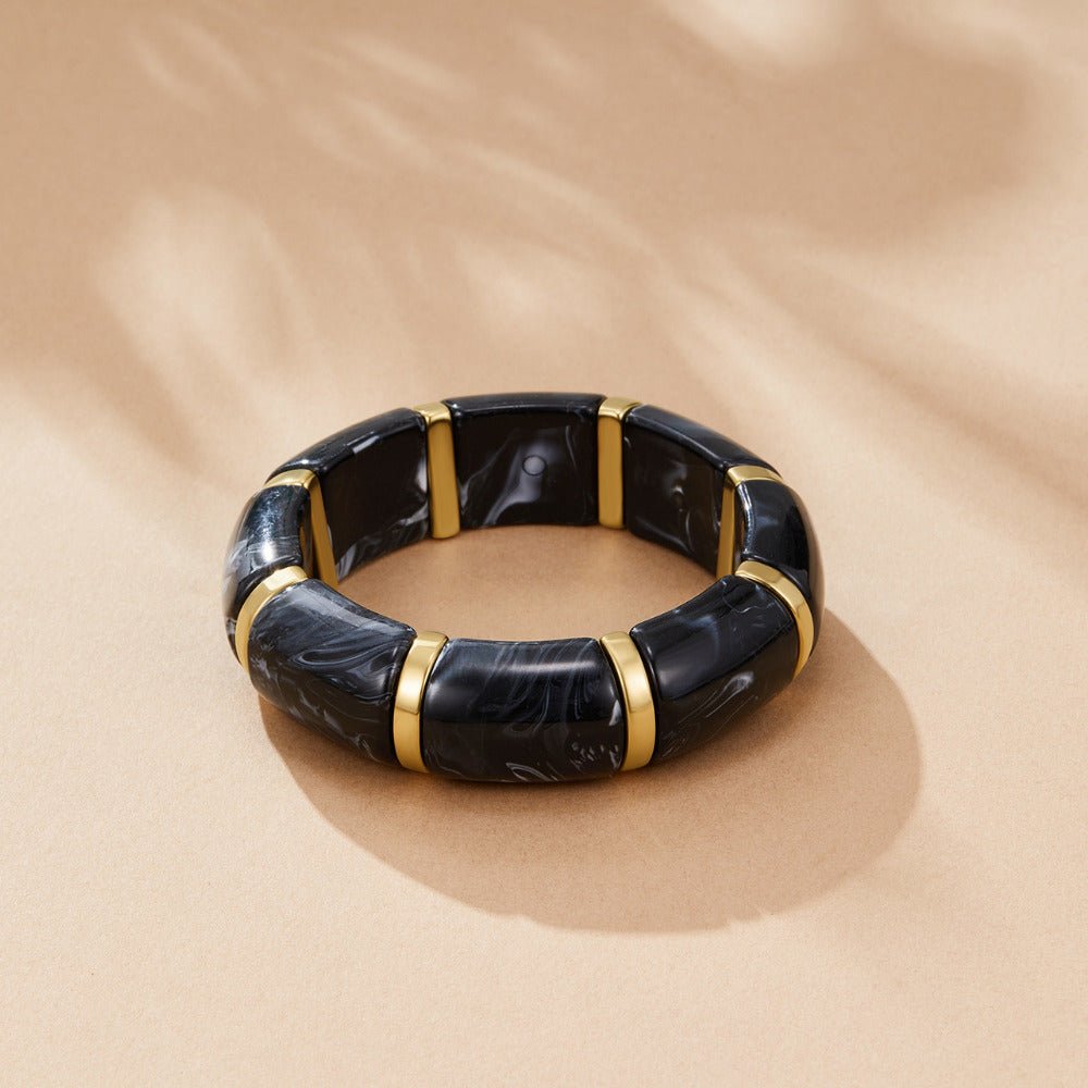 Sabina Black Marbled Bracelet, laid flat on beige surface, black marbled segments with gold