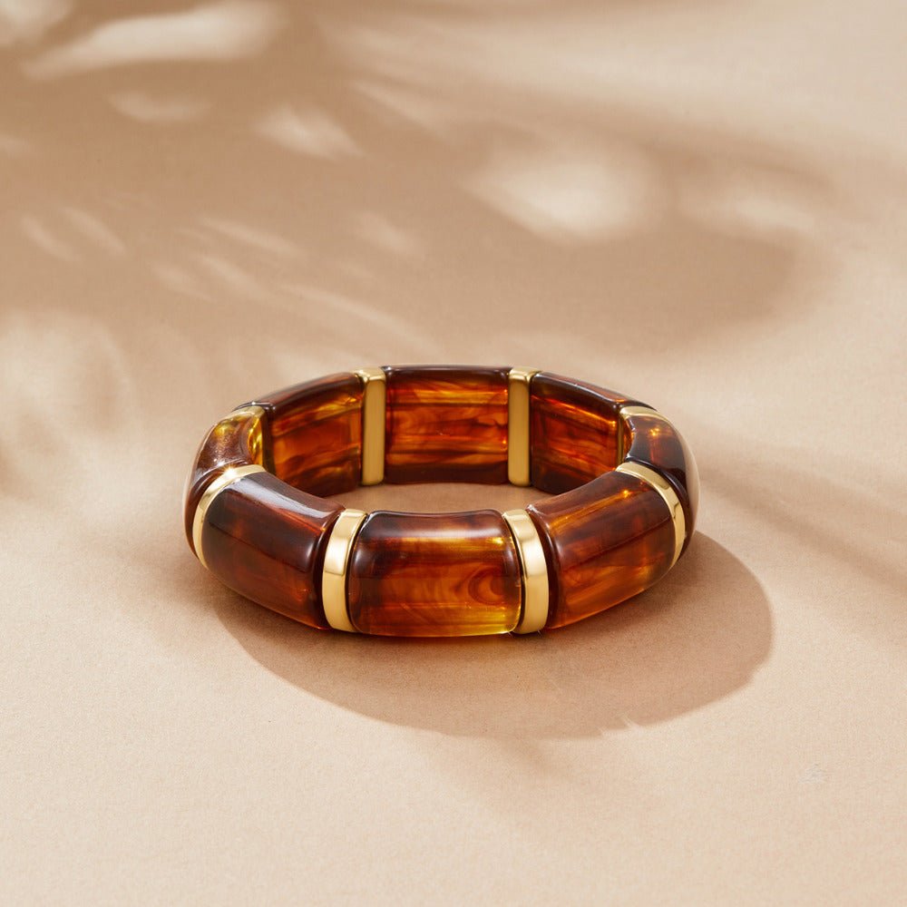 Sabina Golden Brown Marbled Bracelet, lying flat on sand-coloured surface, with shadows across it