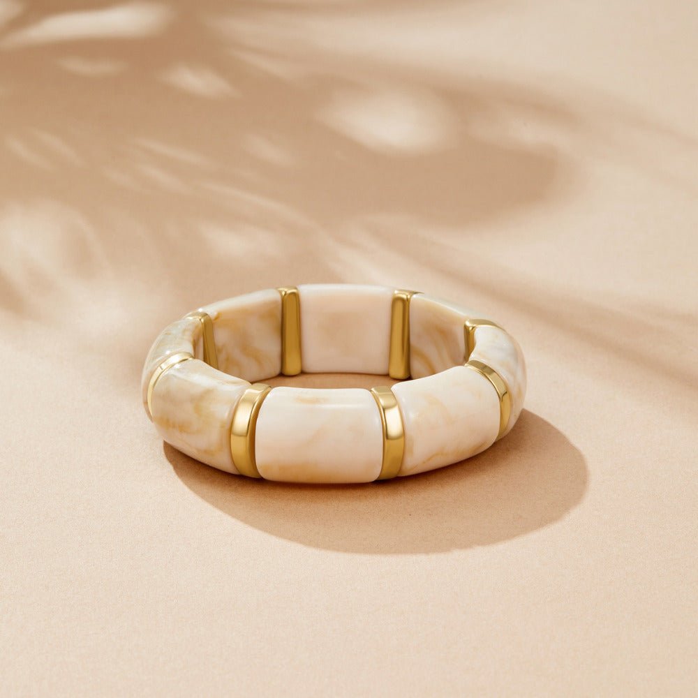 Sabina White Marbled Bracelet, lying flat on a beige surface, cream marbled segments with gold