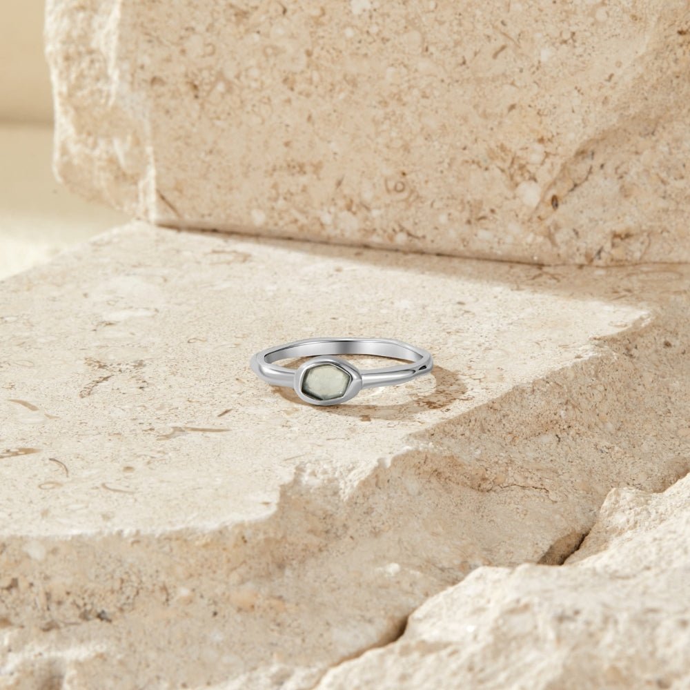 Selene Silver Moonstone Ring, silver ring with a hexagonal grey-green stone, resting on stone