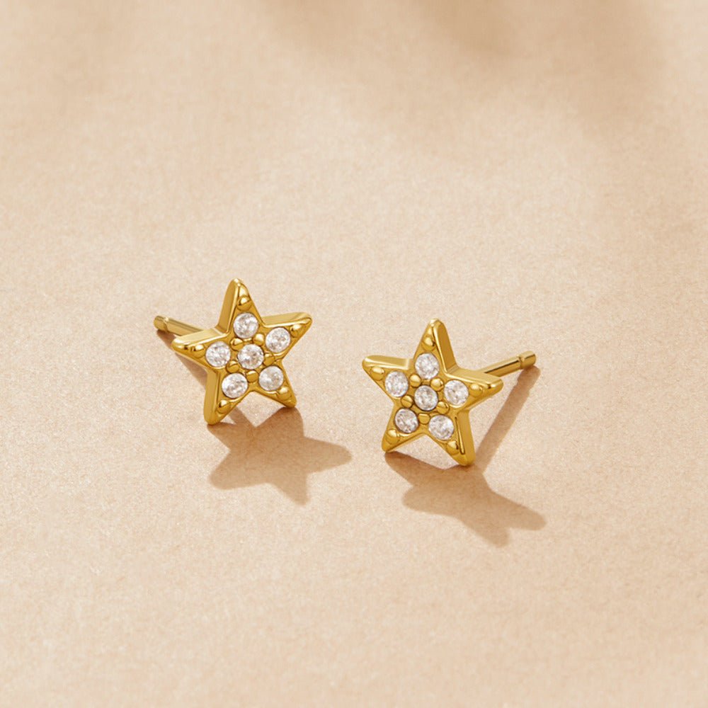 'Shooting Star' Stud Earrings, a pair of star studs on a beige surface, with small clear stones
