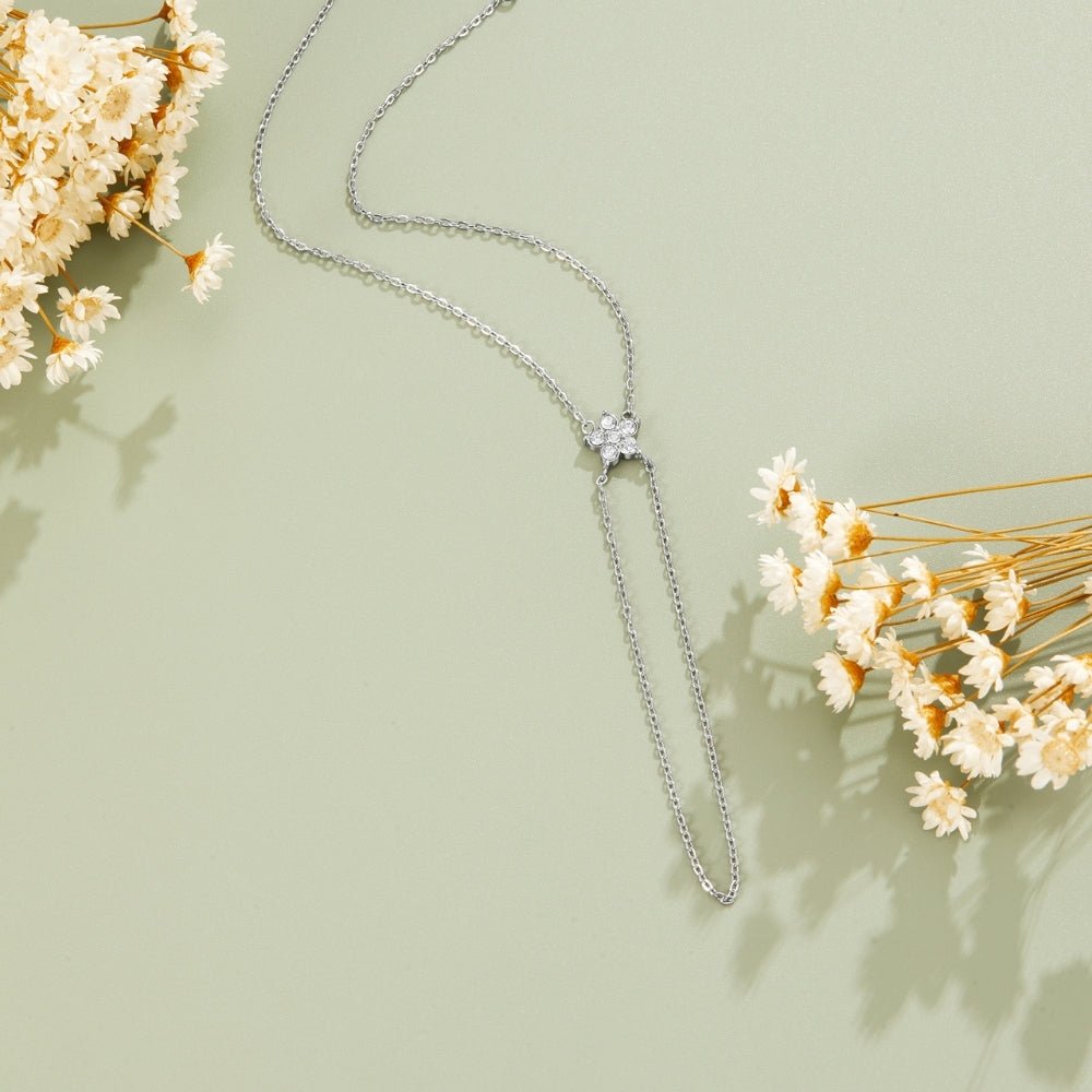 Silver & Crystal Bloom Lariat Bracelet, laid flat on sage green with dried white flowers around it