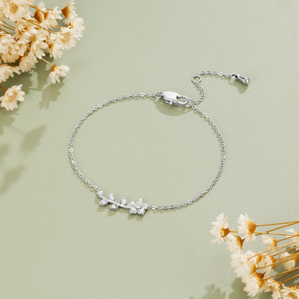 Silver Crystal Vine Bracelet, laid flat on sage green with dried flowers at the corners