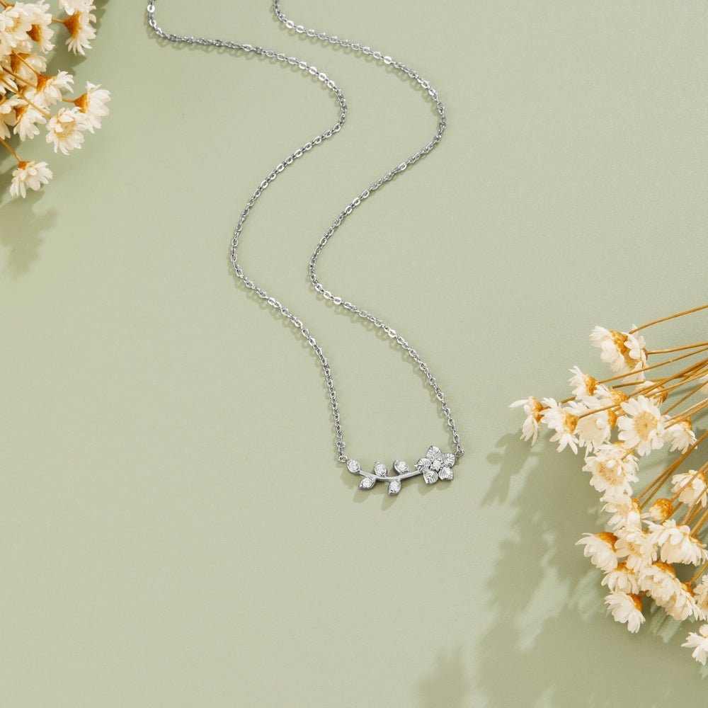 Silver Crystal Vine Necklace, laid flat on pale green with dried white flowers