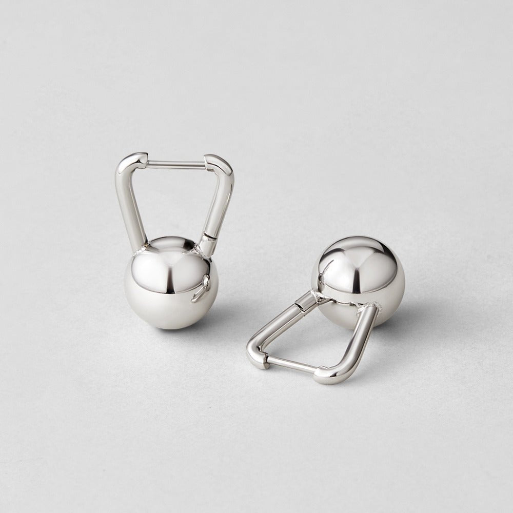 Silver Dumbbell Hoop Earrings, two polished silver hoop earrings lying on a pale grey surface