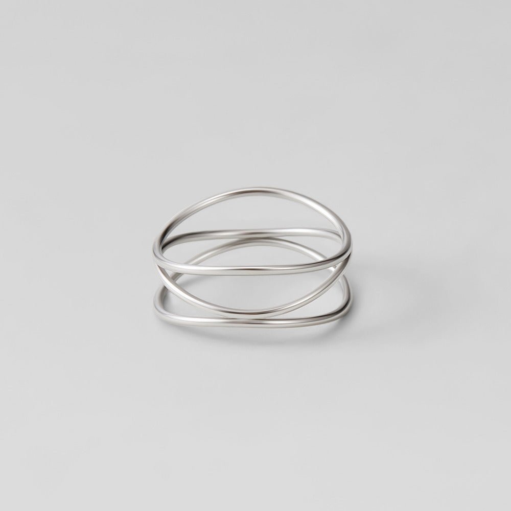 Silver Infinity Loop Ring, lying flat on grey, polished silver wire crossing loops