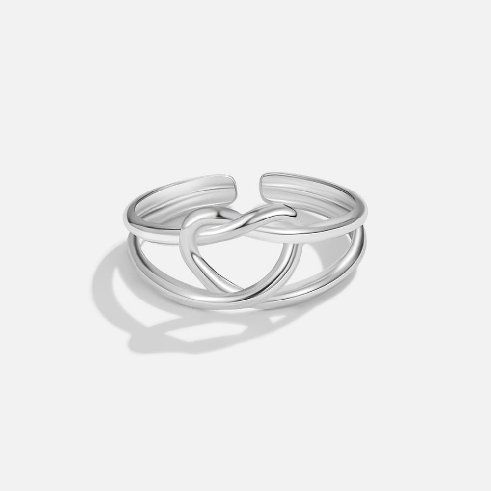 Silver Love Knot Ring, polished silver ring with a twisted heart-shaped knot on a plain background