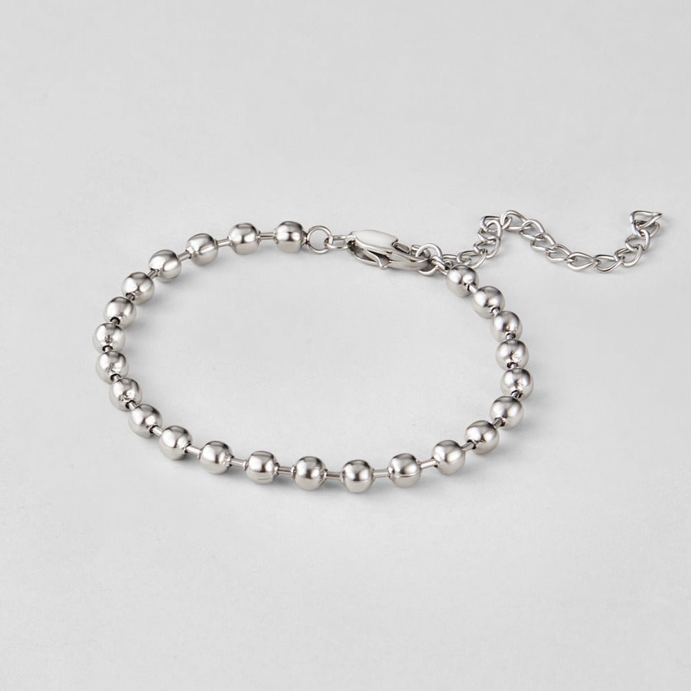 Silver Lulu Bead Bracelet, laid flat on a pale grey surface, silver ball-bead chain with clasp