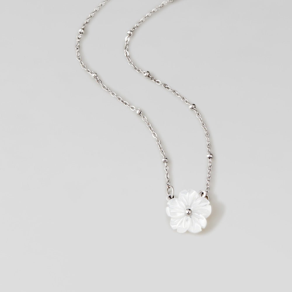 Silver White Blossom Flower Necklace, laid out on a grey surface, silver chain with white