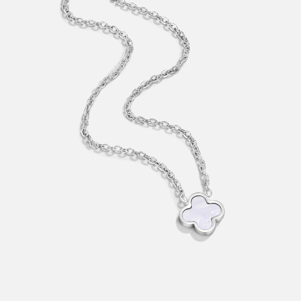 Silver White Clover Necklace, laid flat on light grey, pendant at lower right, white inlay