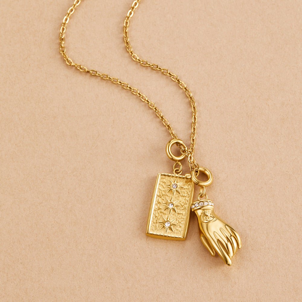 Simple Chain Charm Necklace, gold chain necklace laid flat with a star-engraved tag and a hand charm