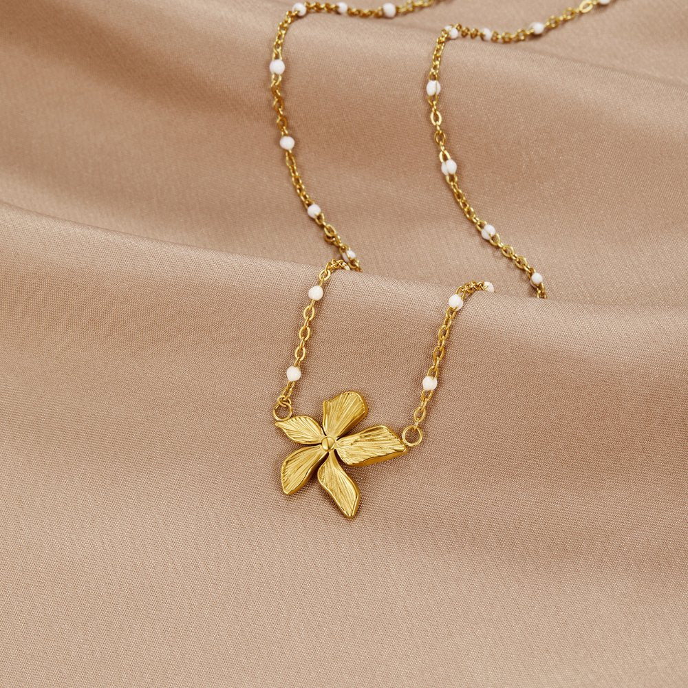 βSpring Bloomβ Bead Necklace, laid flat on beige satin, gold flower pendant on beaded chain