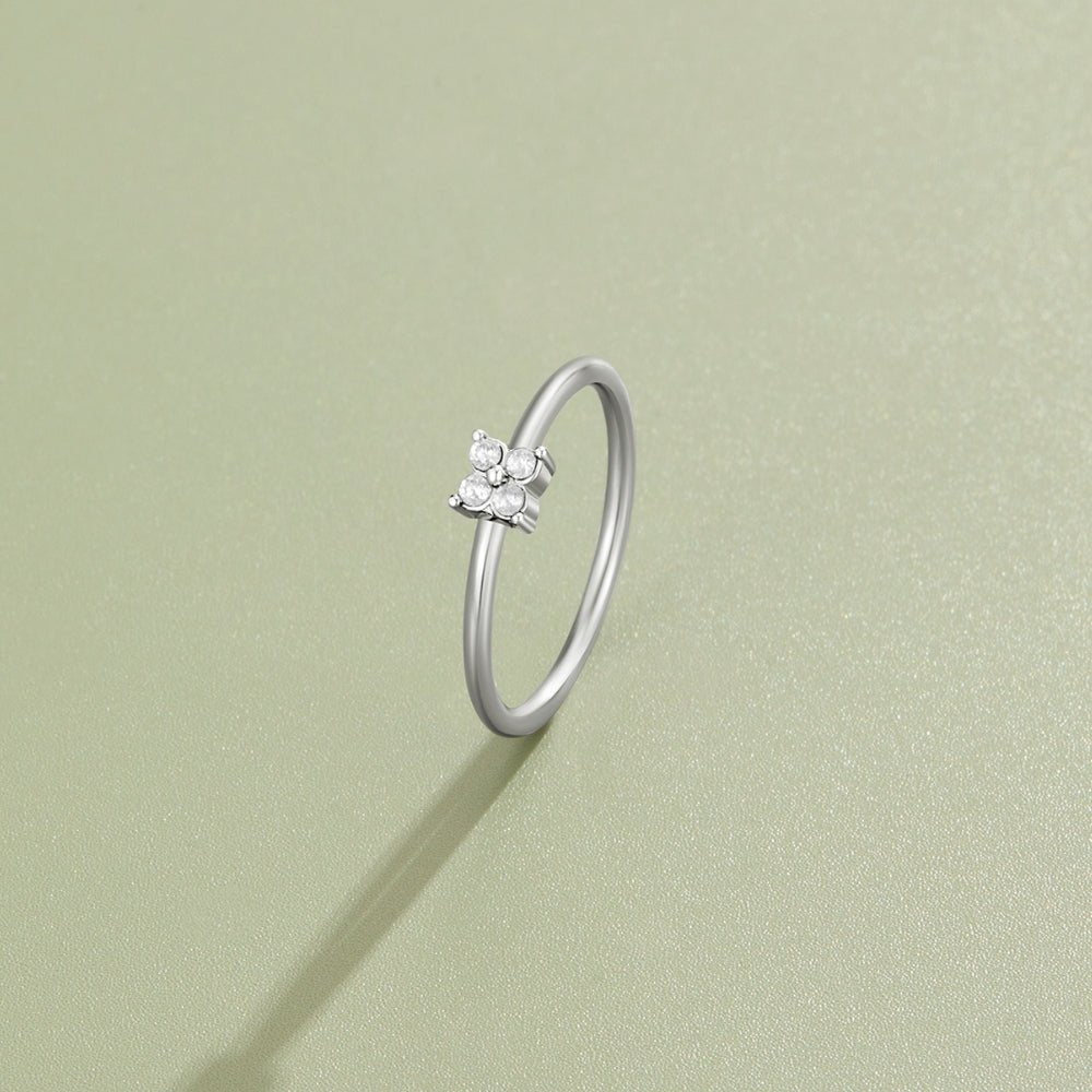 Tiny Petal Silver Ring, standing upright on a pale green surface, four small stones in a