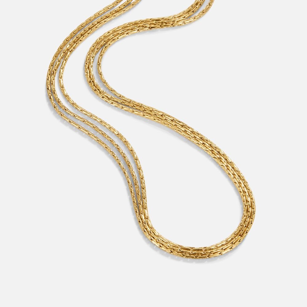 Vina Gold Multi Layered Chain Necklace, three gold chains lying in a loose S-curve on white