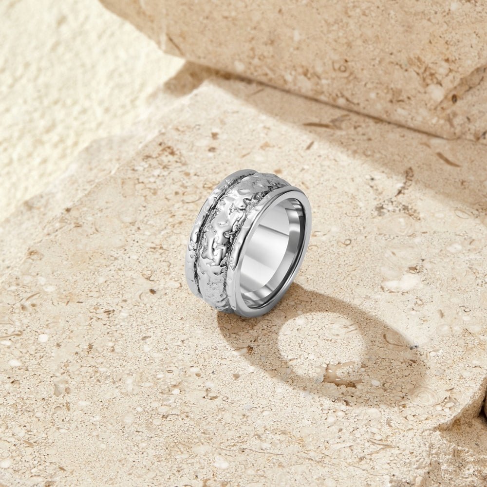 Vintage Elodie Silver Ring, standing upright on a sandy stone surface, textured silver band