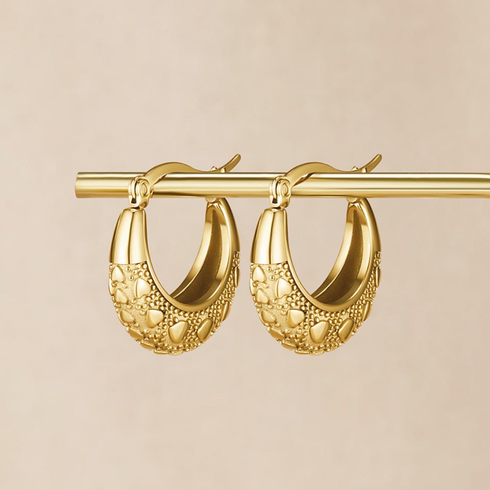 Vintage Gold Cleofe Earrings, pair of gold hoops hanging on a gold bar against beige, textured