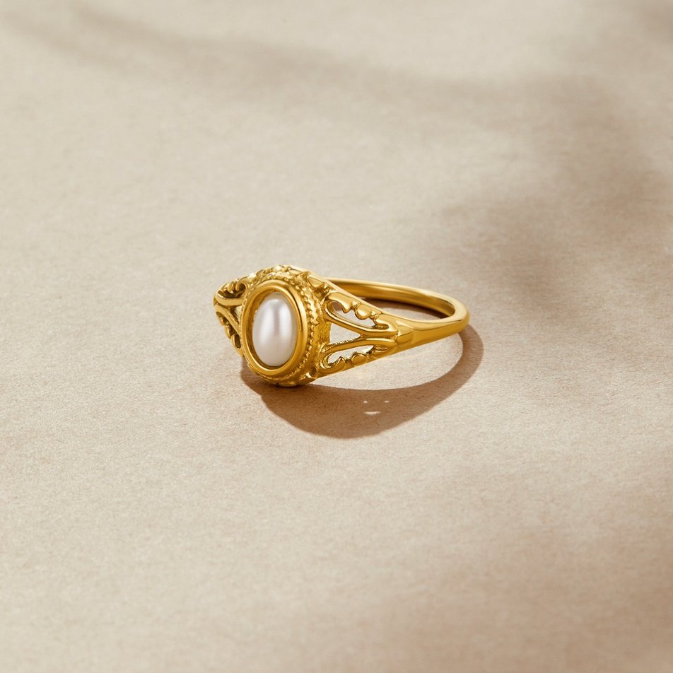 Vintage Royal Pearl Ring, gold ring with an oval pearl on a beige surface