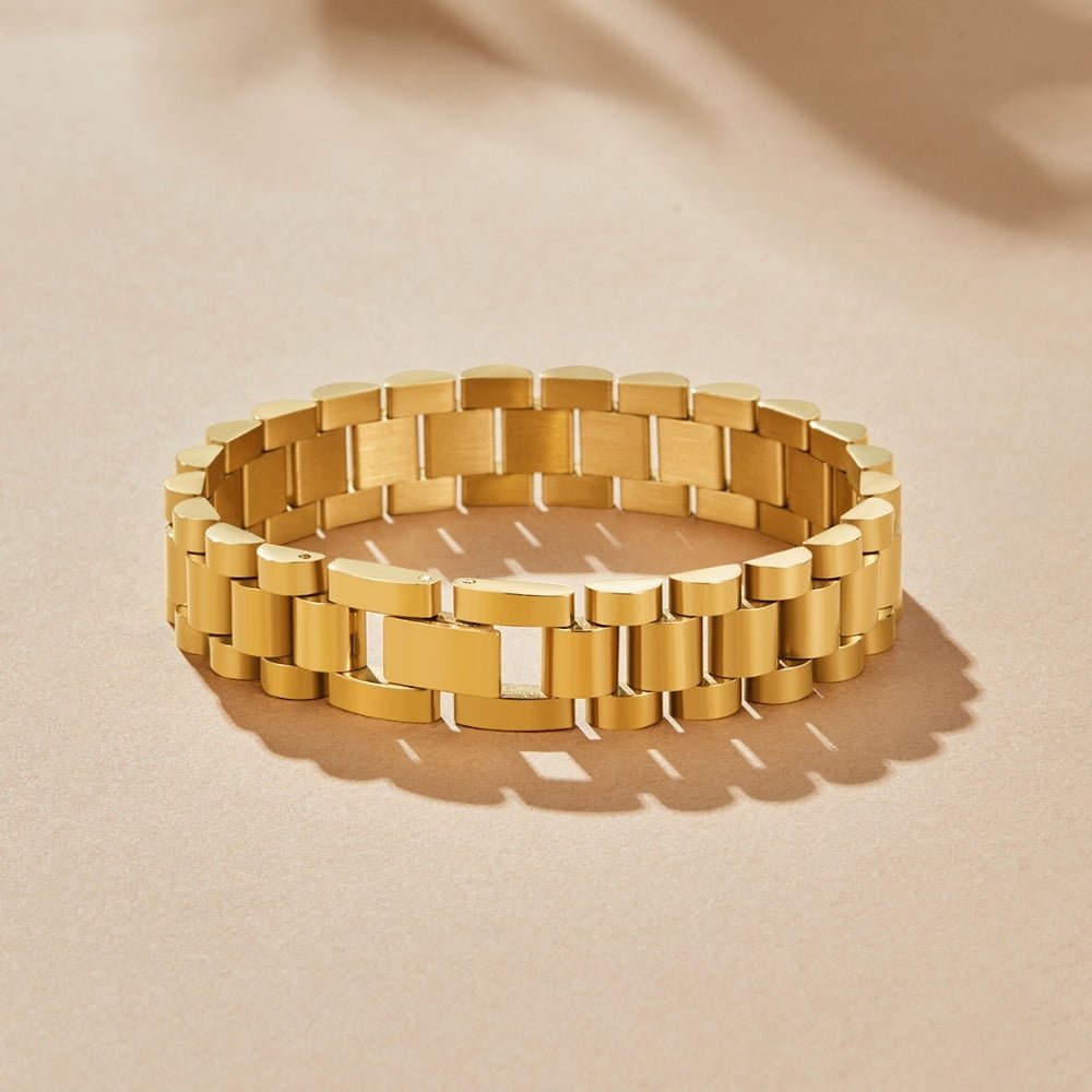 Watch Chain Bracelet, lying flat on sand-coloured surface in sunlight, polished gold links