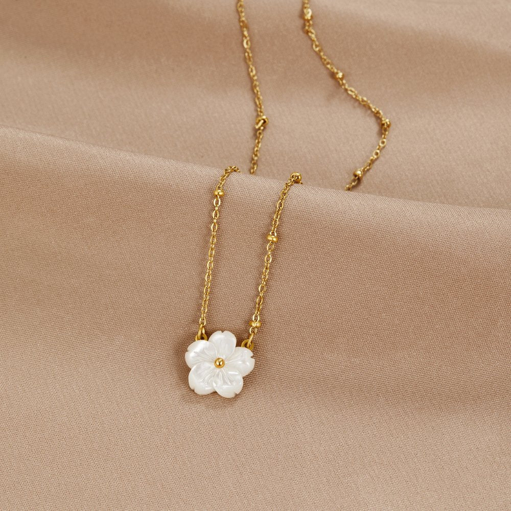 White Blossom Flower Necklace, laid flat on beige satin with a white mother-of-pearl flower pendant