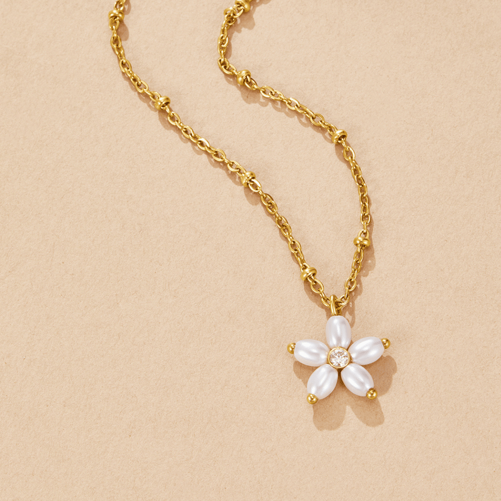 White Flower Pearl Pendant Necklace, flat lay on beige, gold chain with beads and flower pendant