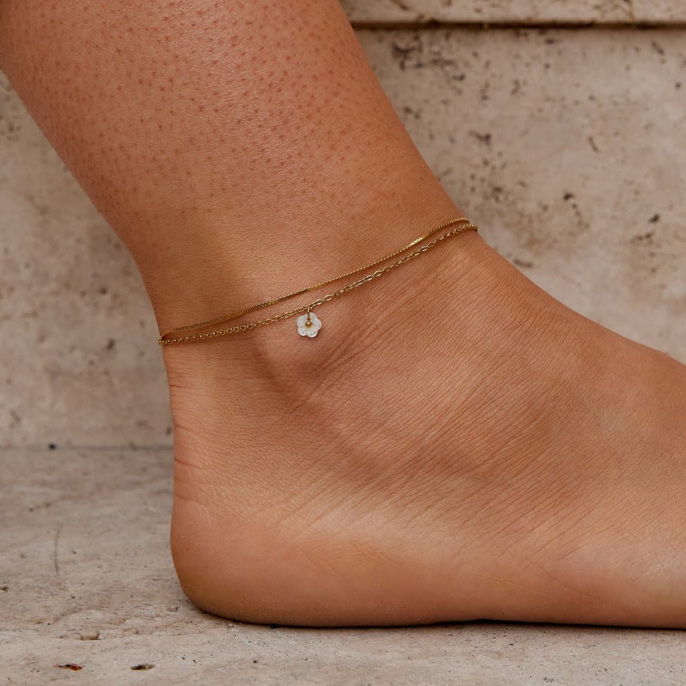 White Petal Shell Layered Anklet, worn on an ankle, with a small white flower charm