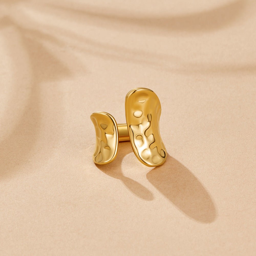 Yuna Geometric Gold Ring, open band ring on a beige surface with hammered gold finish