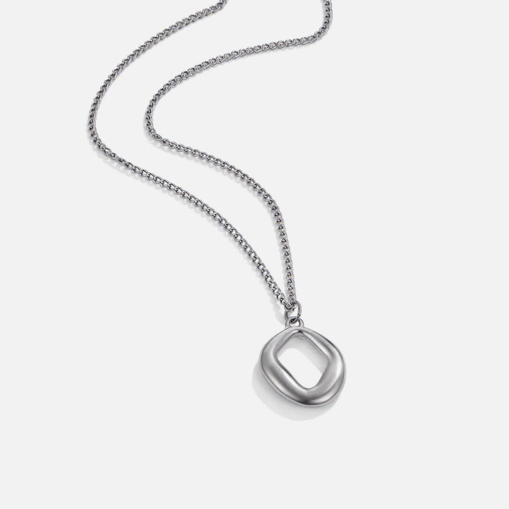 Zola Geometric Silver Necklace, laid flat on white, chain curving to a silver pendant