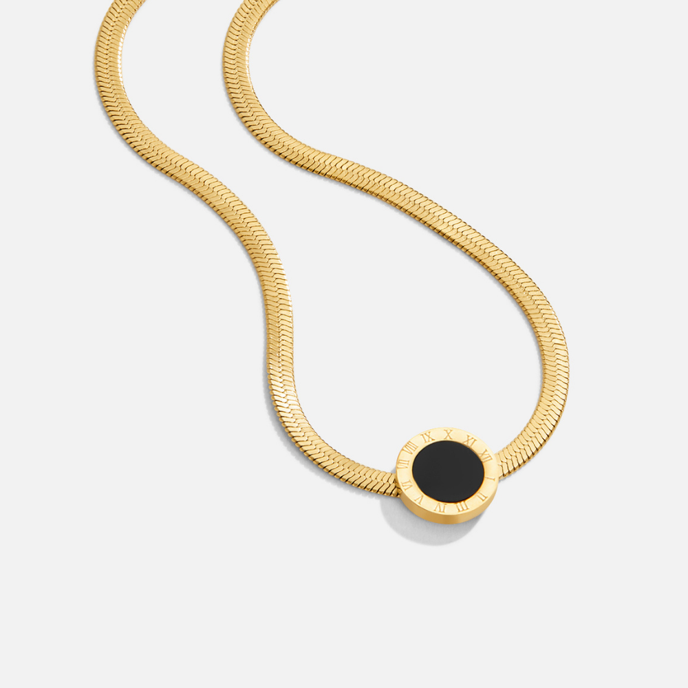 Azalea Black Pendant Necklace, lying flat on white, gold herringbone chain with black round pendant