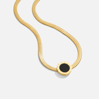 Azalea Black Pendant Necklace, lying flat on white, gold herringbone chain with black round pendant