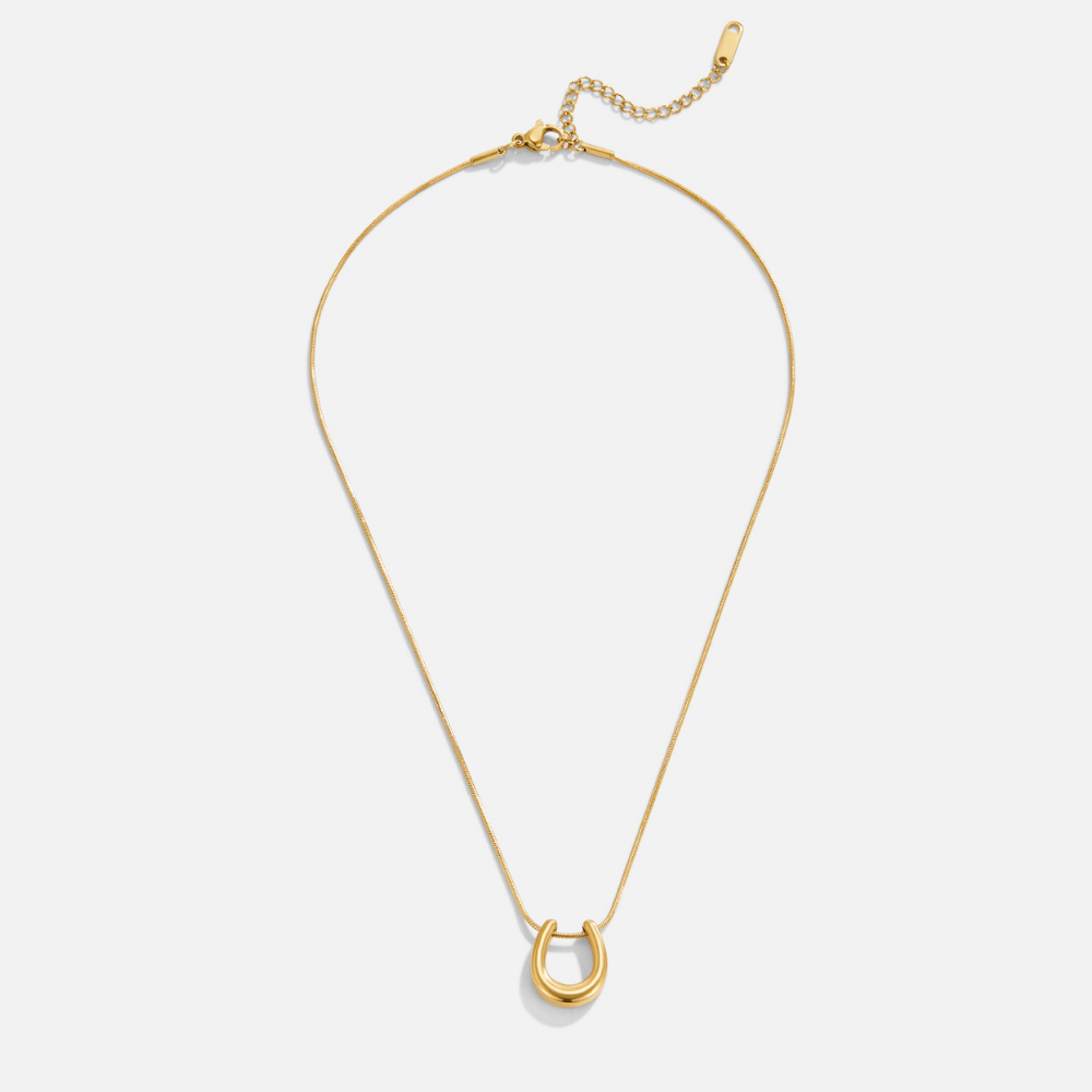 Golden Horseshoe Necklace, flat lay of a thin gold chain with a horseshoe pendant