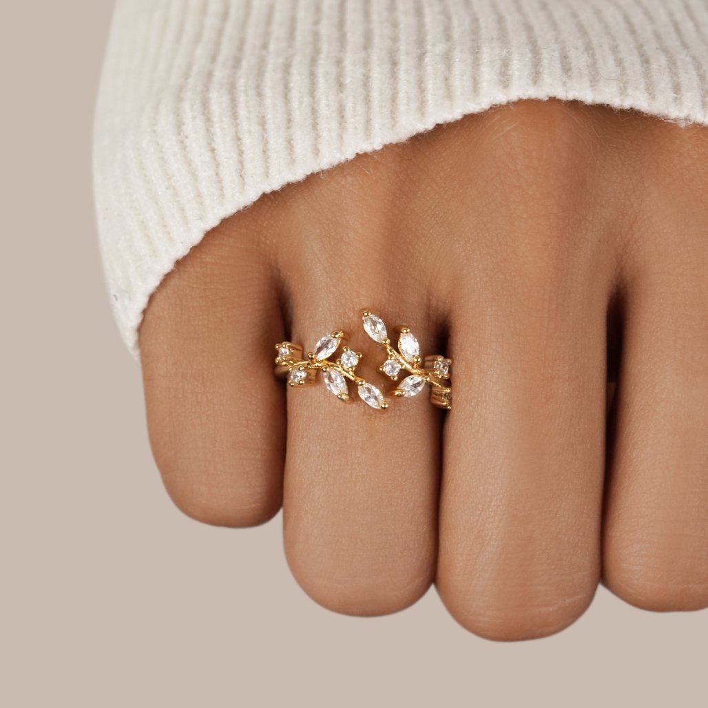18K Gold Crystal Vine Ring, worn on a finger with a cream knit sleeve, gold leaf-and-vine setting
