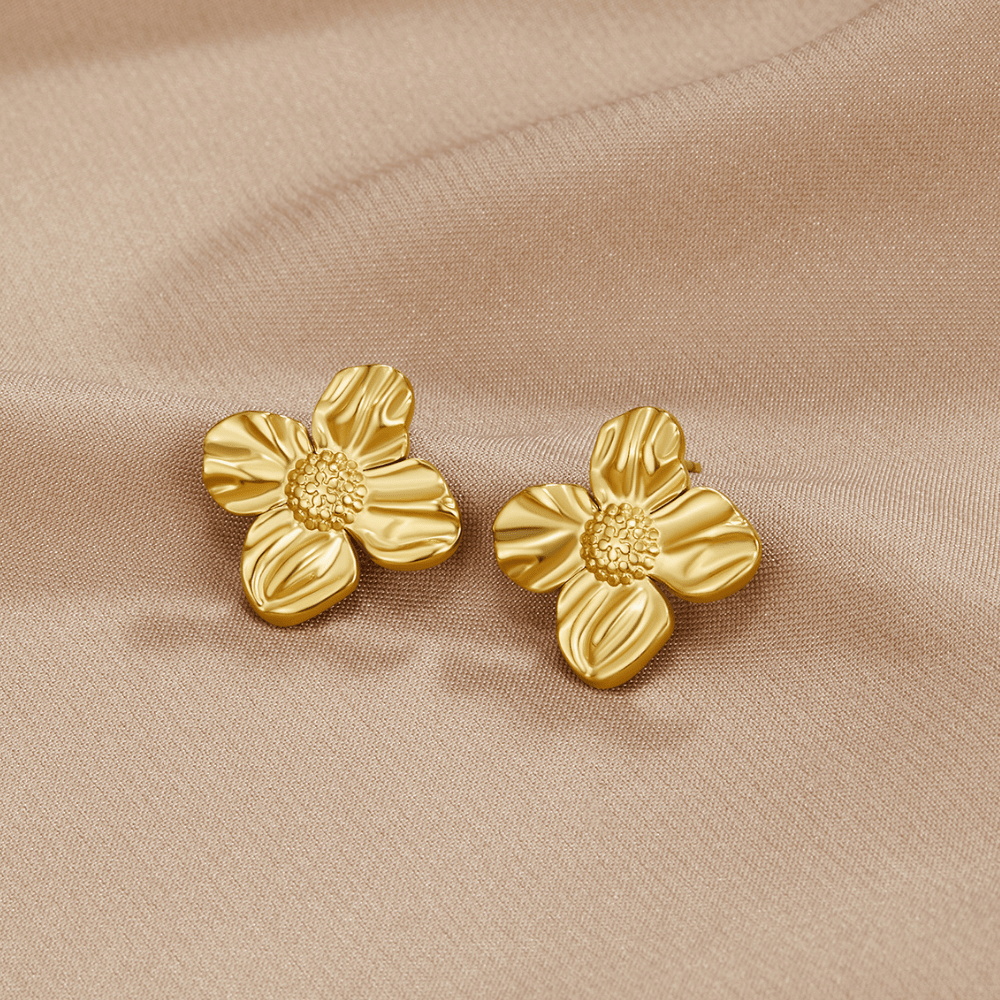 18K Gold Flower Earrings, a pair of four-petal gold earrings lying on beige satin fabric
