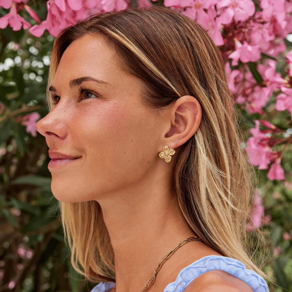 18K Gold Flower Earrings, worn on an ear of a woman in profile, gold flower stud